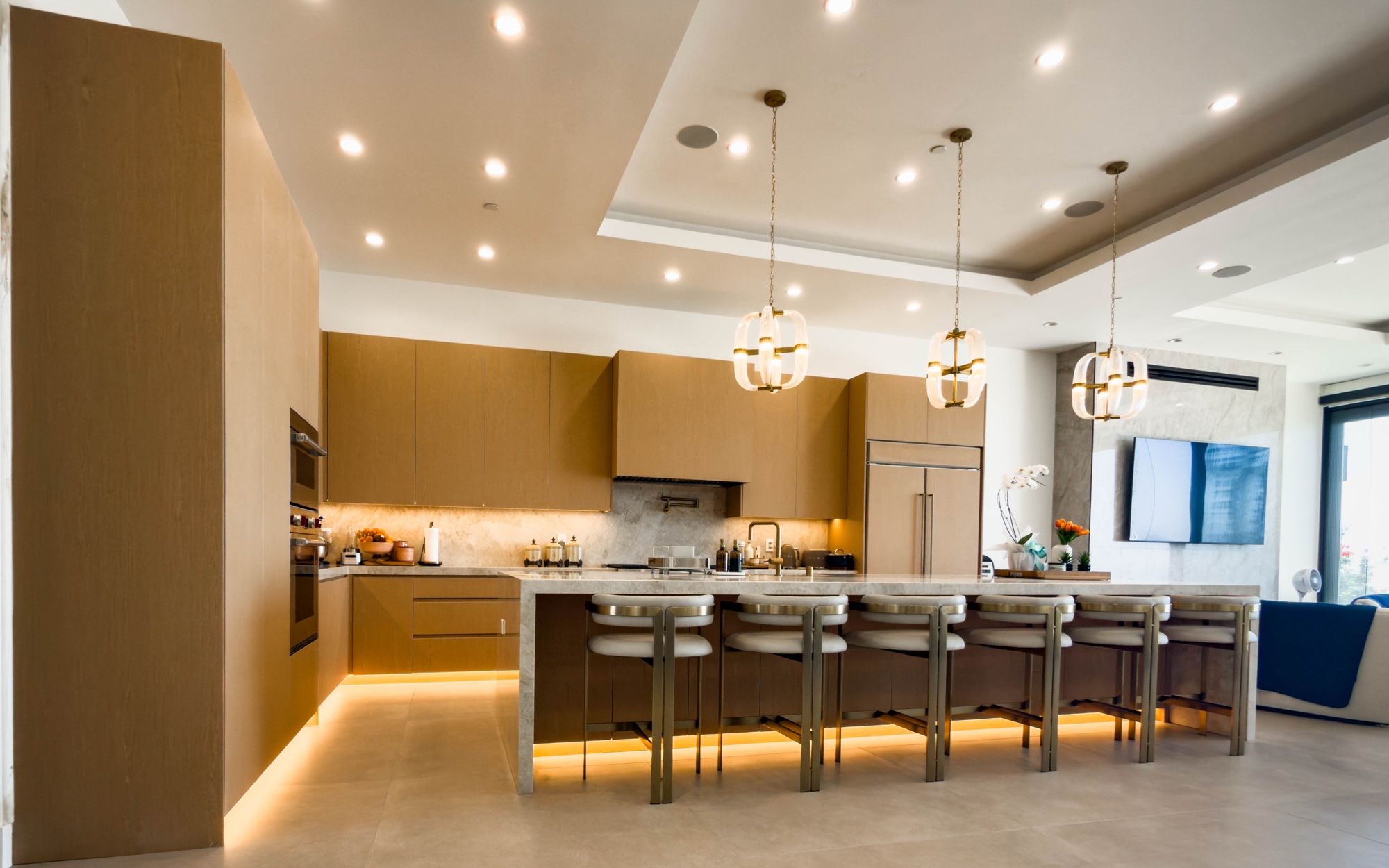 Open white oak kitchen with an under-lit island seating ten